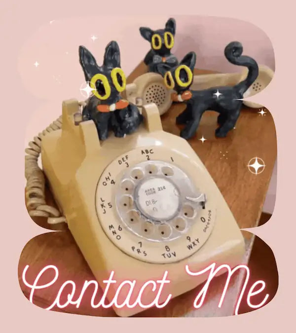 Vintage rotary phone with black ceramic cat figures on and around it, with text saying "Contact Me".