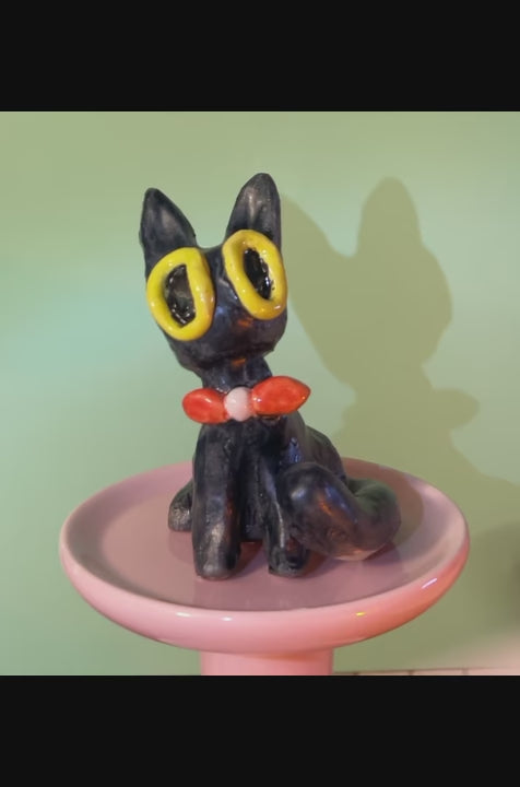 sitting black cat ceramic figurine with tail curled in front of its paw, wearing red bow tie